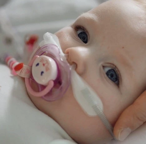 A close up of a baby with a pacifier in its mouth